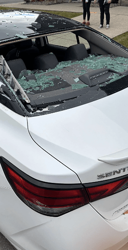 An image of a white car whose back windscreen is broken